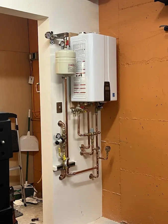 Plumbing technician inspecting water heater connections in Denton